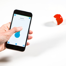 Hand holding a phone with the joystick drive mode driving a red Sphero Mini robot toy.