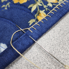 A blanket stitch creates a simple pattern along the edge a blue quilt's binding