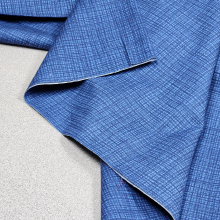 Blue fabric is unfolded and prepared for measuring and cutting