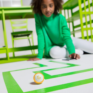 Girl coding Sphero Mini STEM robot through a maze.