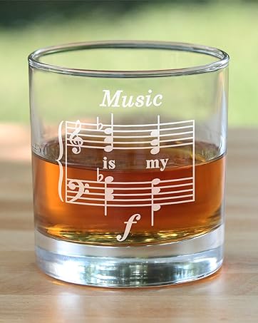 Text says music is my forte, engraved onto a rocks glass. With a backyard background